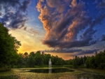 sunset over a fountain in a pond
