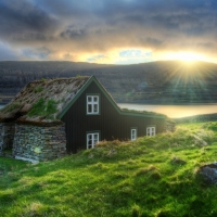 stone cabin with a grass roof by a river at sunset hdr
