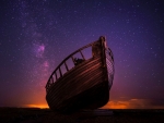 Small, old boat contrasted against starry sky