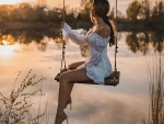 Brunette straddling the swing at sunrise