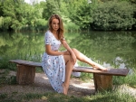 Blonde model sitting on bench by pond
