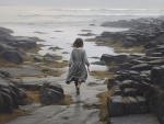 A girl walks on a rocky shore