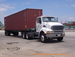 TRUCK HAULING CONTAINER AT THE HARBOR
